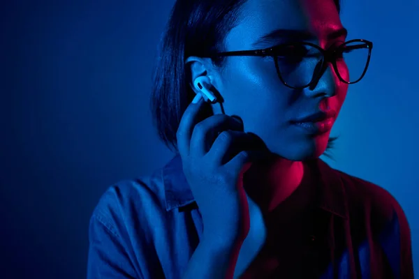 Woman in earbuds in studio with neon lights
