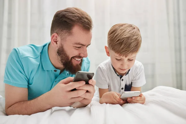 Vader en zoon met behulp van gadgets in slaapkamer — Stockfoto