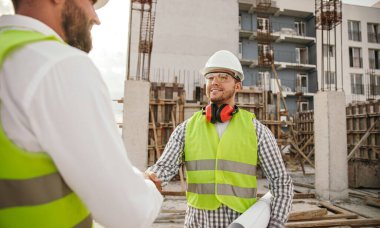 Erkek müteahhit iş arkadaşıyla tokalaşıyor