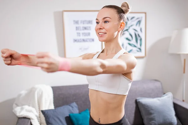 Fit woman doing exercises with resistance band at home — Stock Photo, Image