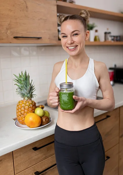 Cheerful woman with green detox drink at home — Stock Photo, Image