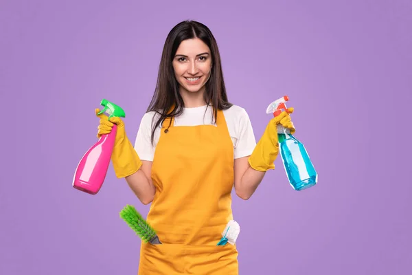 Zufriedenes Dienstmädchen mit Waschmitteln blickt im Studio in die Kamera — Stockfoto