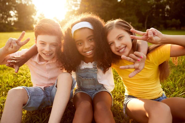 Skupina multiraciálních dětí objímajících se společně v parku — Stock fotografie