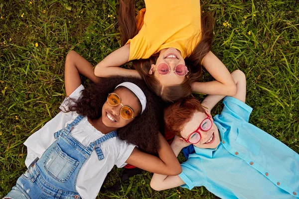 Bedrijf van diverse gelukkige vrienden liggend op gras — Stockfoto