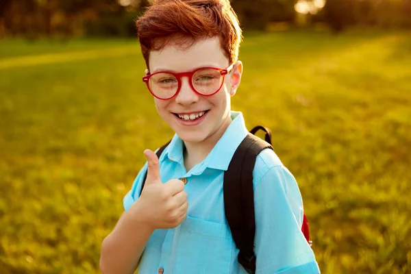 Glimlachende roodharige jongen tonen duim omhoog en kijken naar camera — Stockfoto