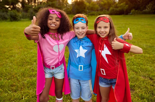 Alegre diversos niños en trajes de superhéroe en el parque —  Fotos de Stock