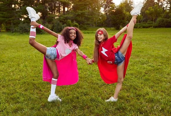 Meninas alegres em trajes de super-herói em pé no parque — Fotografia de Stock