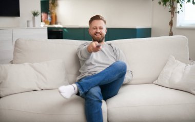 Happy man watching TV on sofa