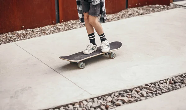 Crop lapsi ratsastus rullalauta jalkakäytävällä — kuvapankkivalokuva
