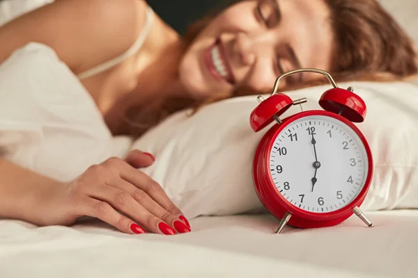 Щаслива жінка в ліжку з будильником вранці — стокове фото