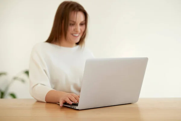 Mulher sorridente trabalhando no laptop à mesa — Fotografia de Stock