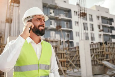 İnşaat mimarı akıllı telefondan konuşuyor.