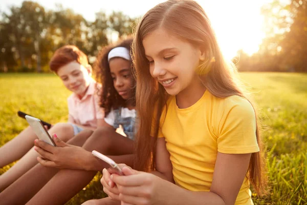 Multiraciale kinderen met behulp van gadgets in park — Stockfoto
