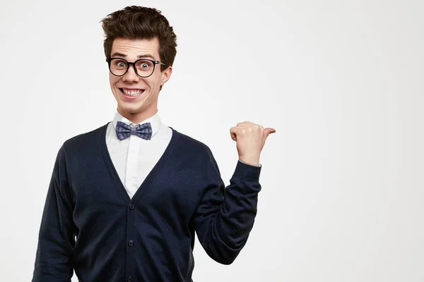Vrolijke nerd in bril wijst weg in de studio — Stockfoto