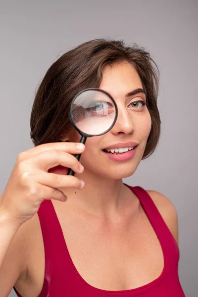 Leende kvinna tittar genom förstoringsglas — Stockfoto