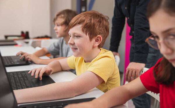 Happy kid learning computer science in classroom