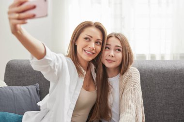 Anne ve kızı evde selfie çekiyorlar.