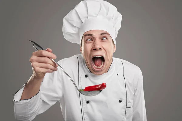 Cozinheiro engraçado tentando prato com pimenta quente — Fotografia de Stock