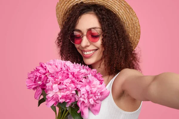 Mujer joven positiva tomando selfie con flores — Foto de Stock