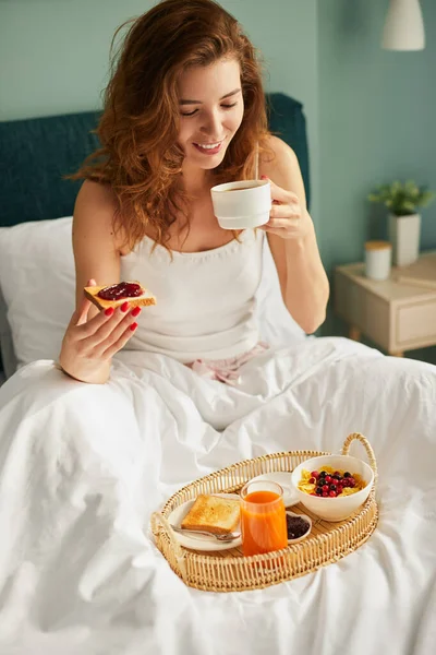 Gelukkig vrouw genieten van ontbijt in bed — Stockfoto