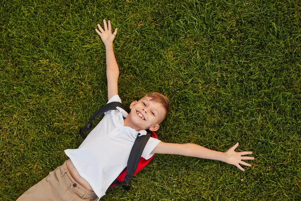 Счастливый школьник лежит на траве — стоковое фото