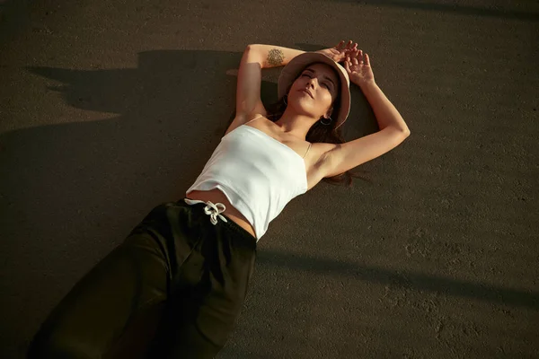 Relaxado mulher milenar deitado na estrada de asfalto — Fotografia de Stock
