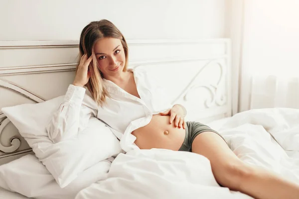 Ευτυχισμένη έγκυος που αναπαύεται στο κρεβάτι — Φωτογραφία Αρχείου