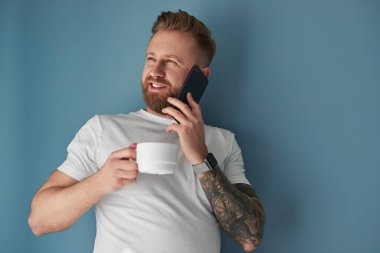 Sıcak içkili adam akıllı telefondan konuşuyor.
