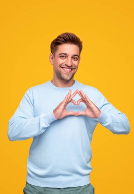 Mutlu adam parmaklarıyla kalp işareti gösteriyor.