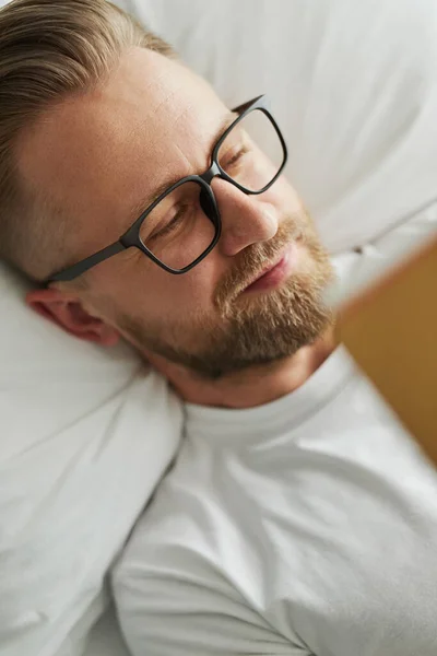 Щасливий чоловік з книгою відпочиває на ліжку — стокове фото