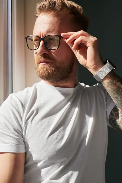 Barbudo hombre en gafas mirando por la ventana —  Fotos de Stock
