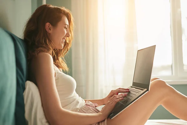 Junge Frau benutzt Laptop im Bett — Stockfoto