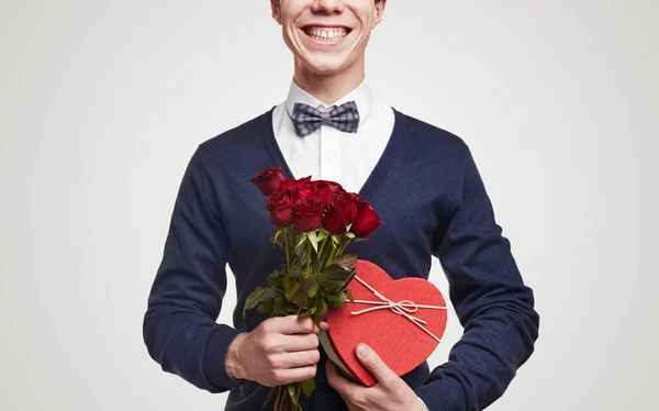 Güller ve hediye kutusuyla neşeli genç adam — Stok fotoğraf