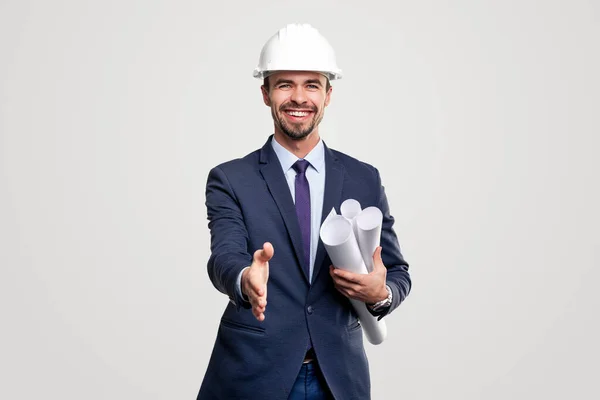 Smiling engineer with blueprints outstretching hand to camera — Stock Photo, Image