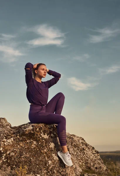 Donna in forma che riposa su una collina rocciosa — Foto Stock