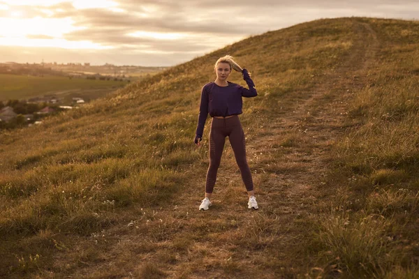 Mulher ativa em sportswear de pé na colina — Fotografia de Stock