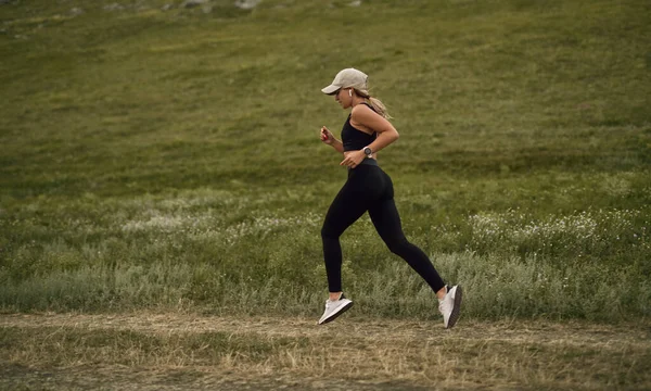 Спортивная женщина бегает в летнем поле — стоковое фото