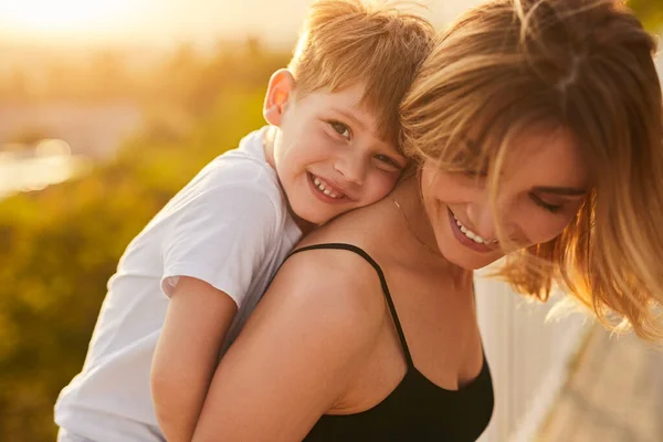 Lycklig mor bär liten son på sommardagen — Stockfoto