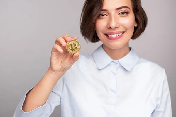 Cheerful woman smiling and showing bitcoin