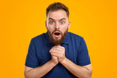 Şok olmuş sakallı adam kameraya bakıyor.