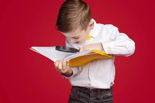 Skolpojke med förstoringsglas läsning bok — Stockfoto
