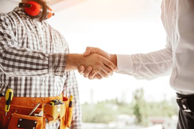 İnşaat alanında yönetici ve inşaatçı el sıkışıyor