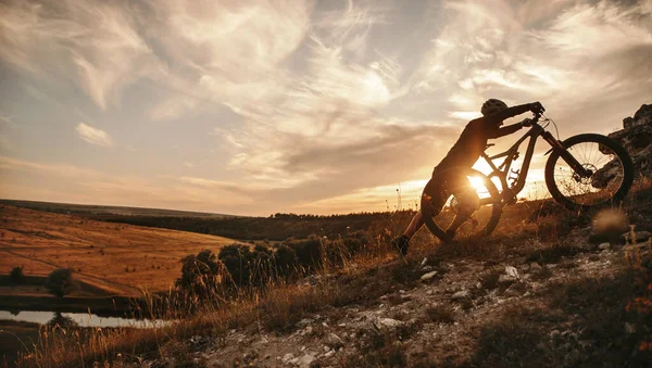 Ciclista com bicicleta de montanha ao pôr do sol — Fotografia de Stock