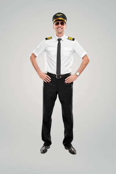 Lachende luchtvaartmaatschappij kapitein met handen op heupen — Stockfoto