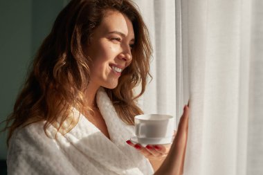 Kahveli mutlu kadın pencereye bakıyor