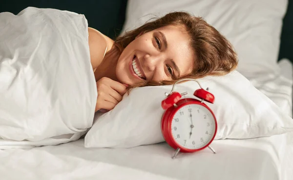 Спляча жінка лежить в ліжку біля сигналізації — стокове фото