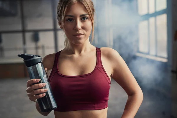 Sportnő egy üveg vízzel az edzőteremben — Stock Fotó