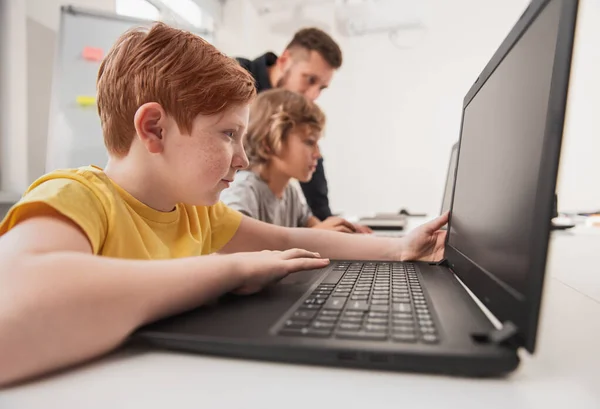 Niño inteligente trabajando en el ordenador portátil en el aula — Foto de Stock