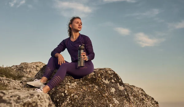 Donna in forma con bottiglia d'acqua a riposo in natura — Foto Stock