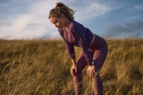 Mujer cansada descansando después de correr en el campo — Foto de Stock